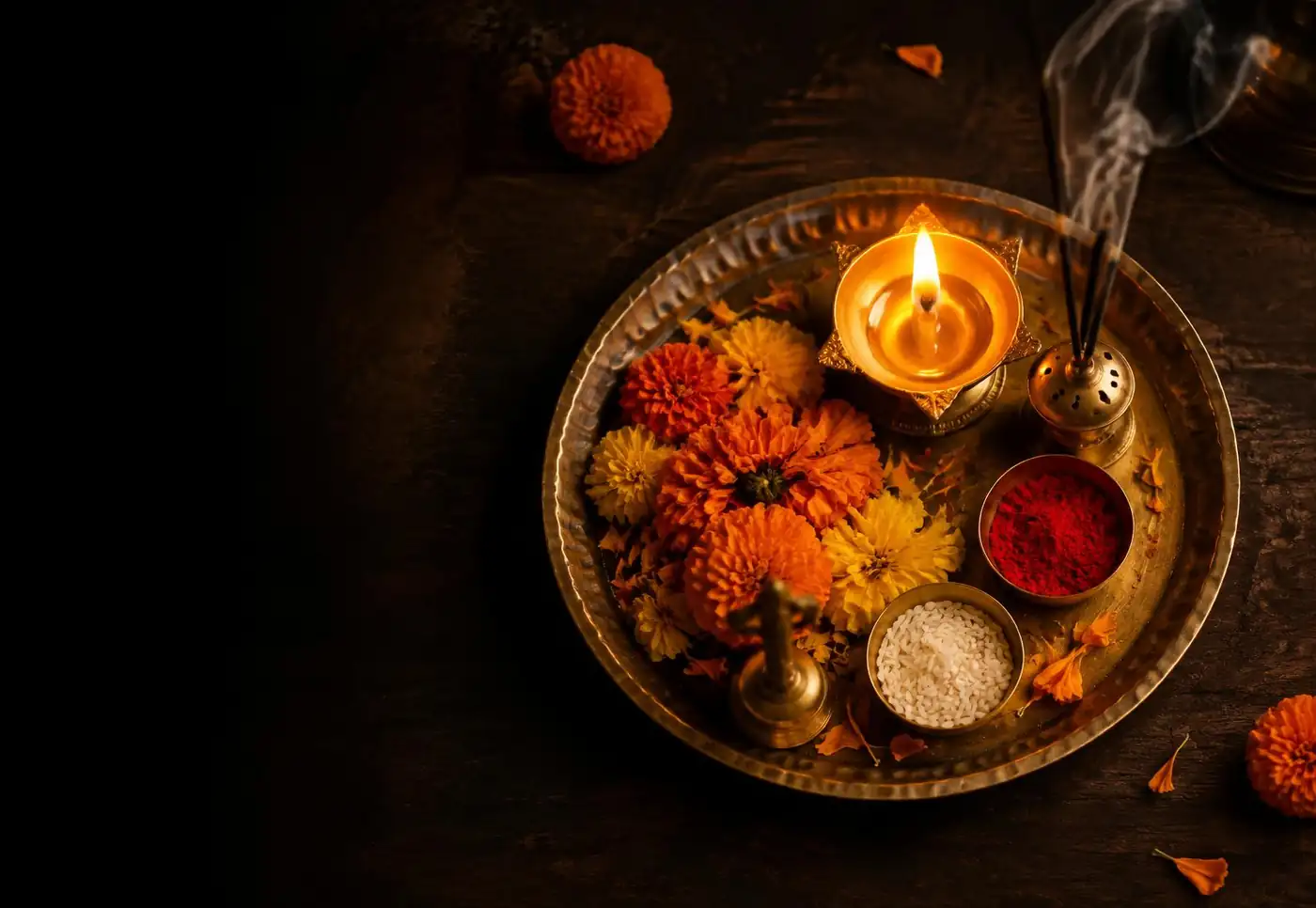 Brass pooja thali with a diya and marigolds